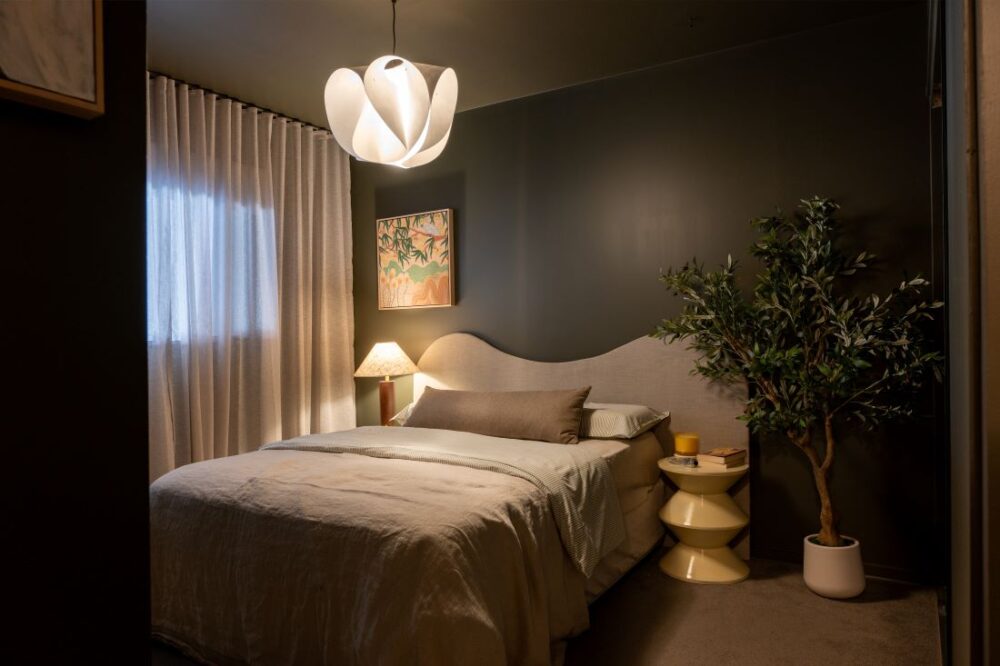 Bedroom with dark green walls, upholstered bed, and indoor plant