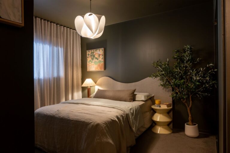 Bedroom with dark green walls, upholstered bed, and indoor plant