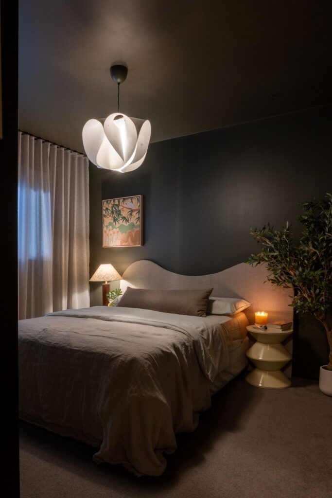 Bedroom with dark green walls, curved bed, and ambient lighting