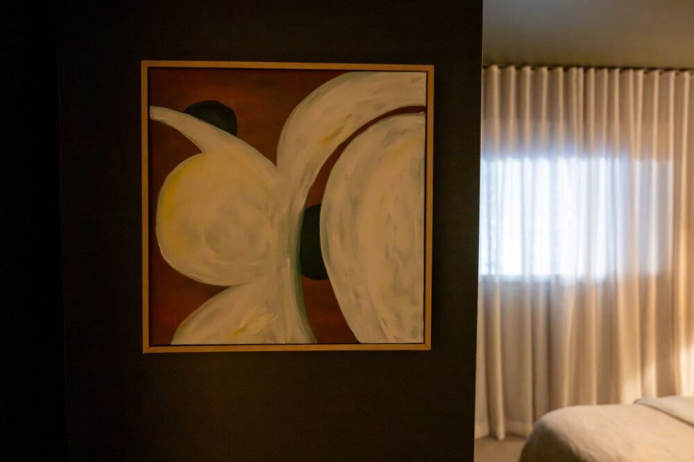 Abstract painting with white and brown tones on dark green wall