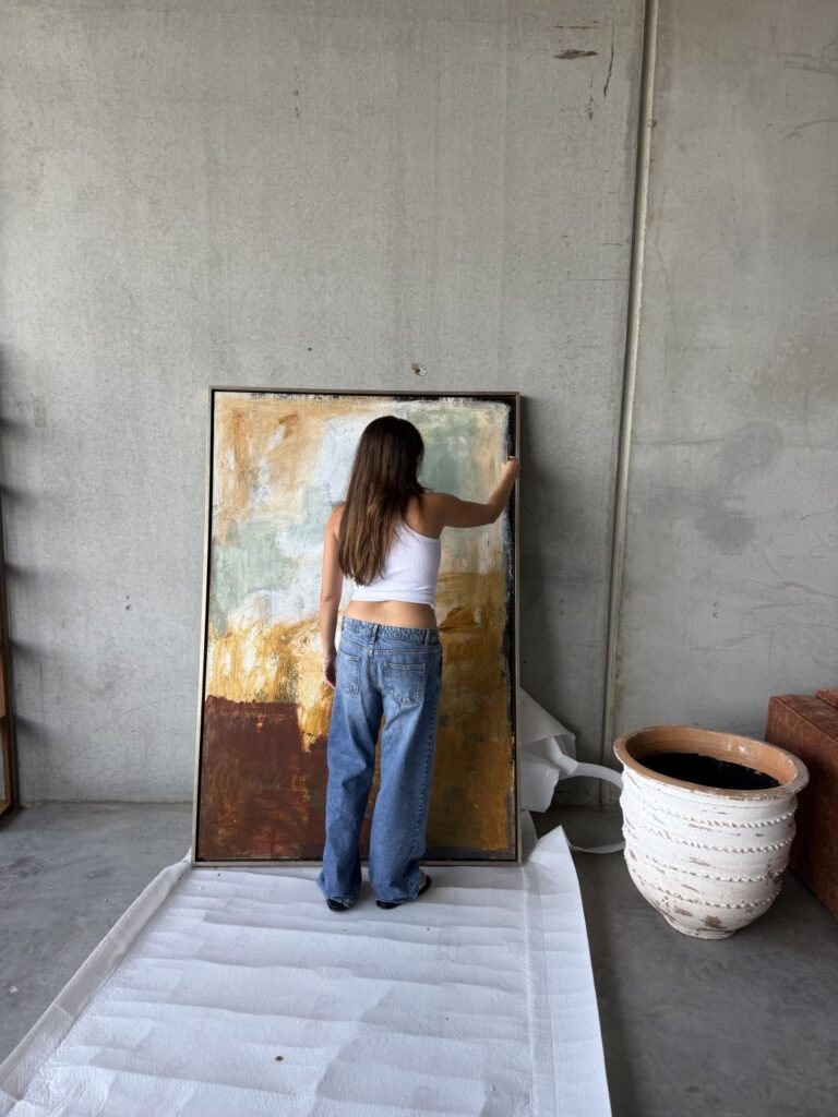 J E N N I F E R L I A standing in front of large abstract painting working on canvas in minimalist studio