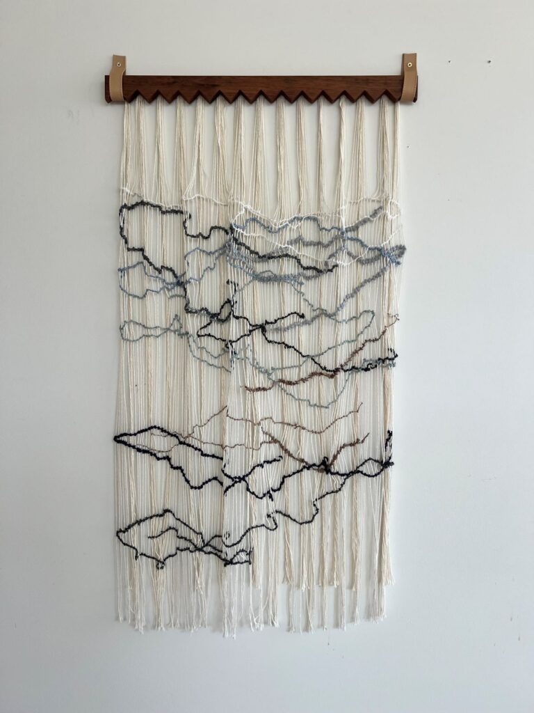 Handwoven neutral textile wall hanging with layered linear patterns