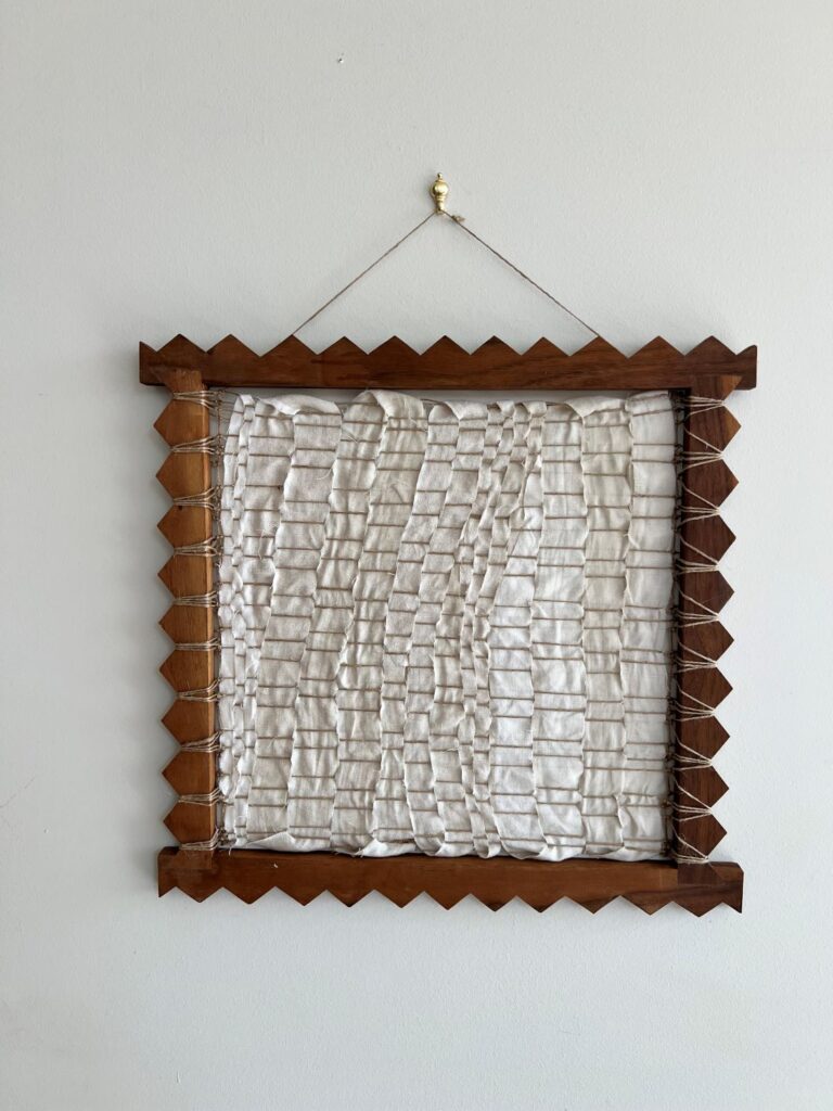Neutral woven textile artwork in wooden frame with zigzag border