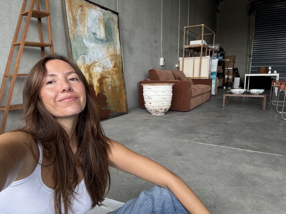 Taking a selfie in a minimalist studio surrounded by abstract paintings and furniture
