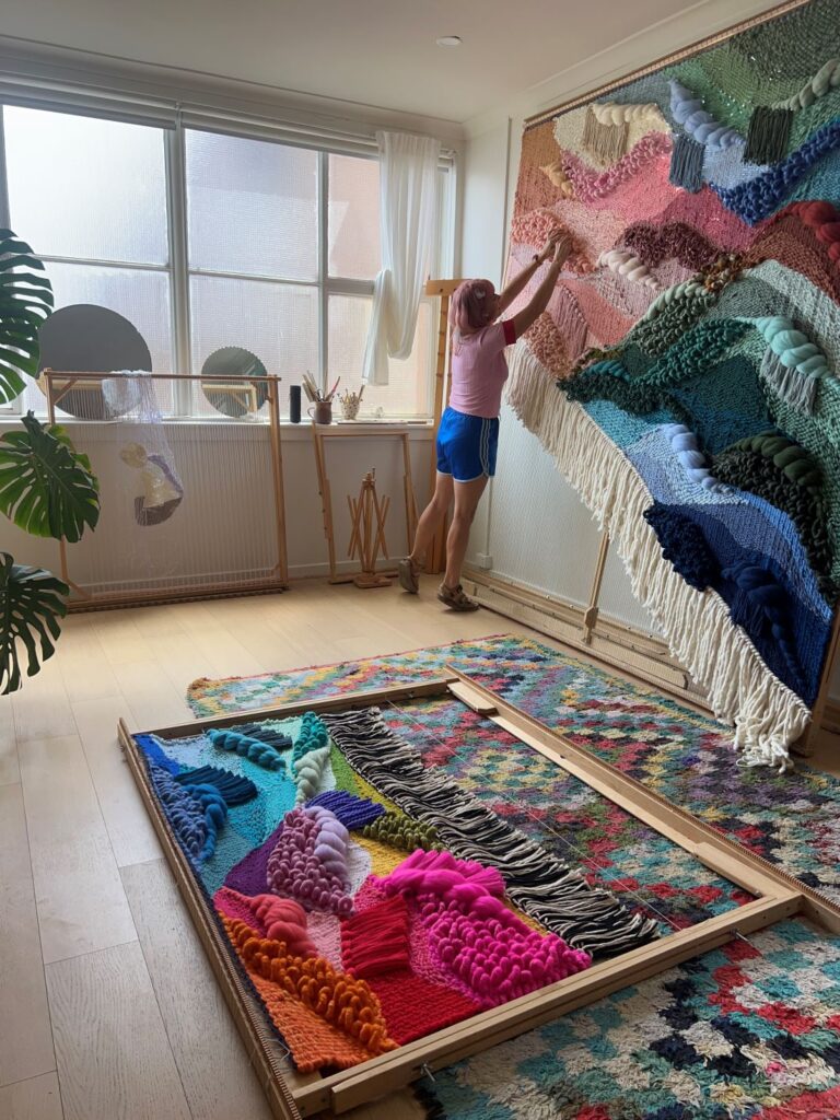 Artist working on large colourful woven textile installation in studio