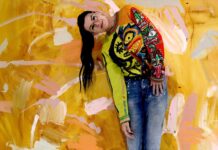 Between instinct and restraint: The bold art of Shayle Flesser Shayle Flesser posing before bright abstract painting