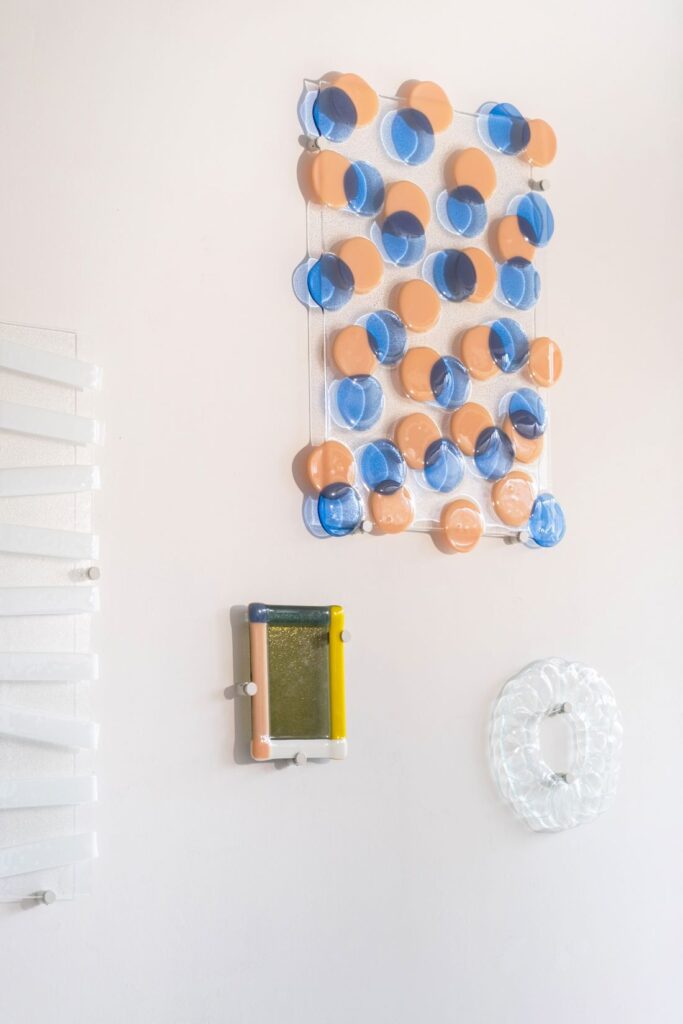 Blue and peach translucent circular samples arranged on a clear panel beside sculptural material studies