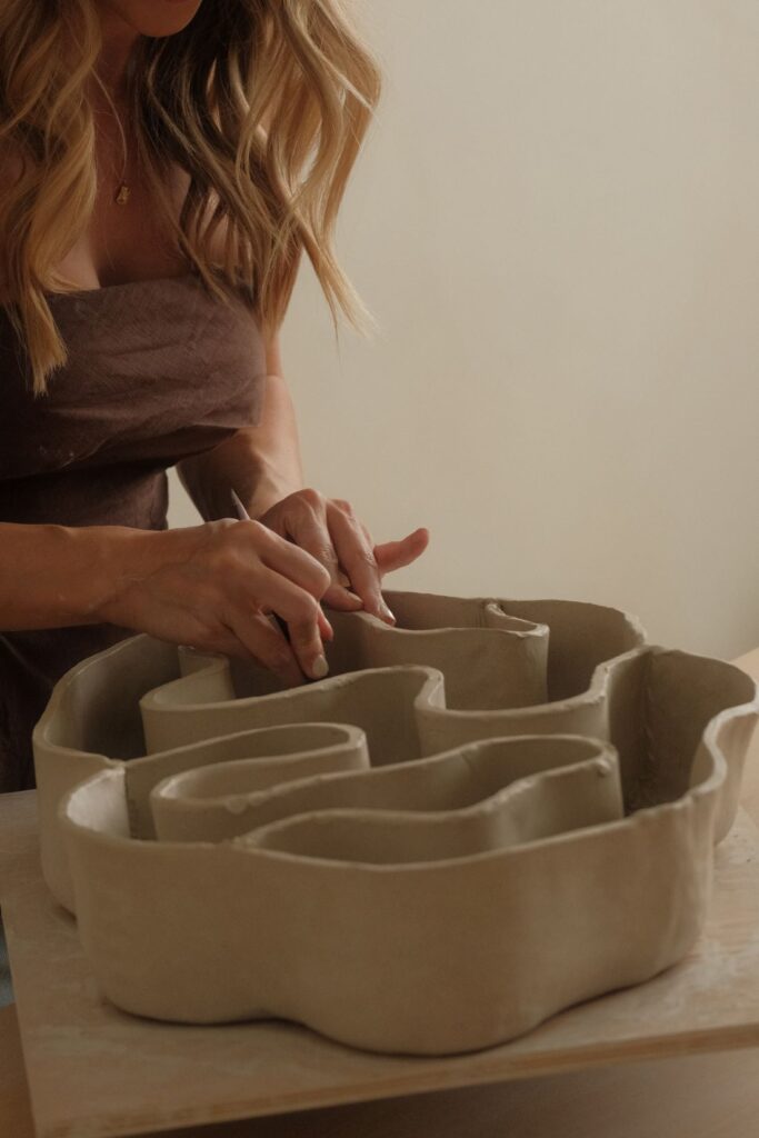 Close-up of a ceramic artist shaping the curved internal walls of a large hand-built clay sculpture.
