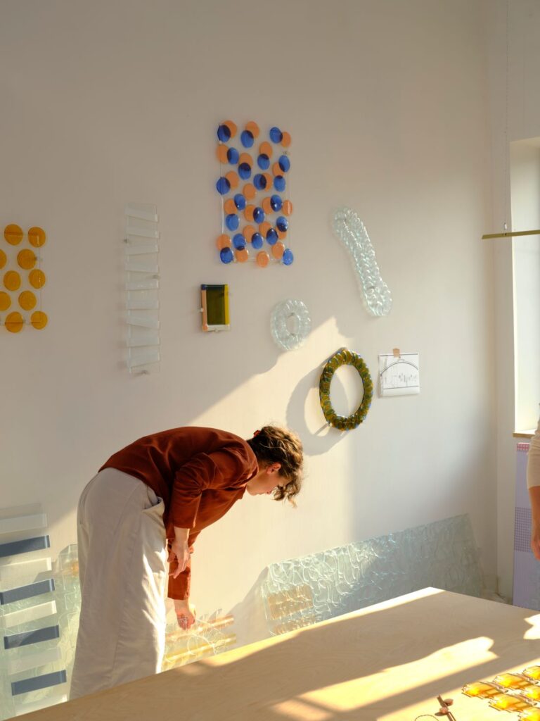 A+N Studio designer examining translucent material samples in a sunlit workspace filled with colourful prototypes