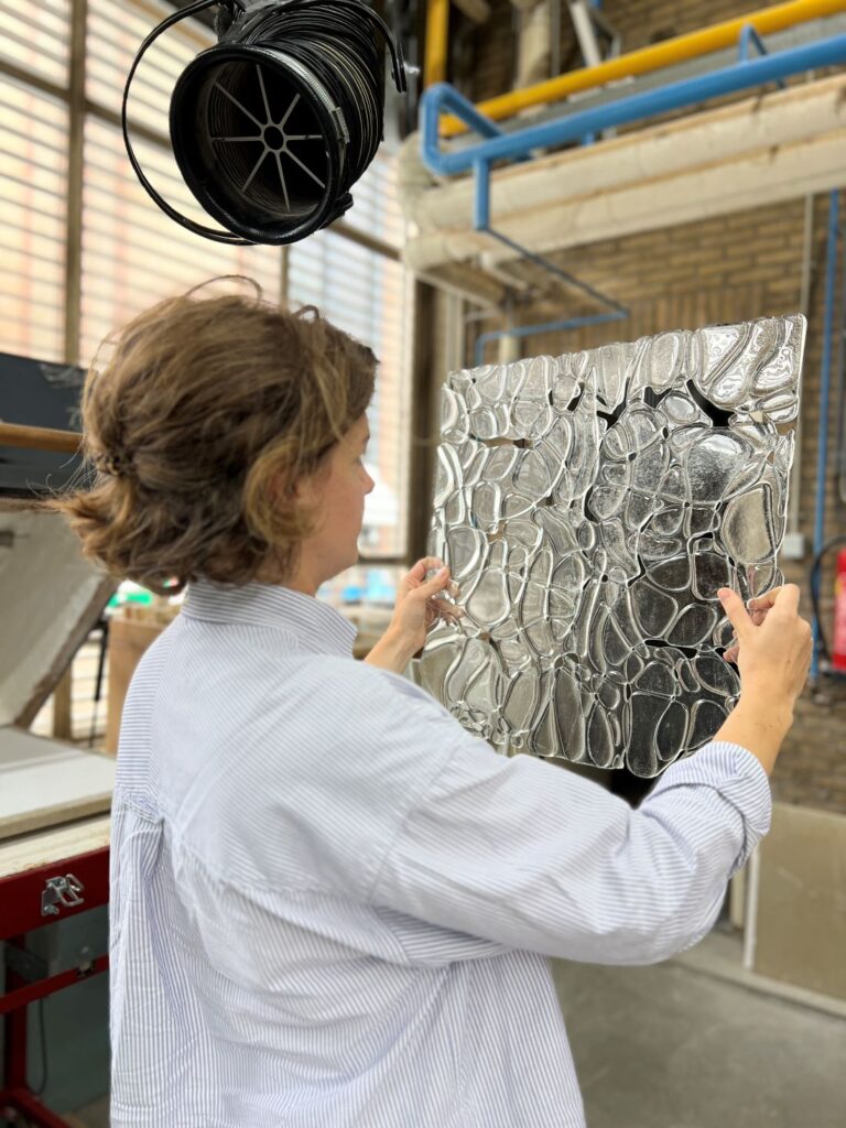 Designer holding a large clear textured panel inside an industrial workshop