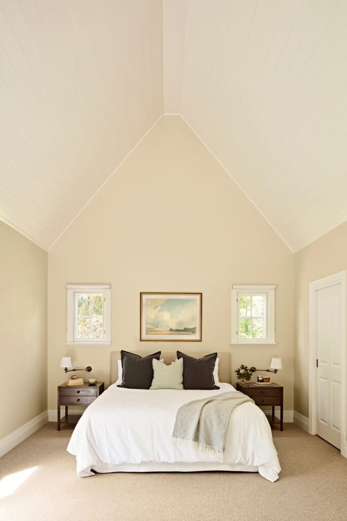 Serene bedroom with a vaulted white lining-board ceiling, neutral walls, timber bedside tables and layered charcoal and sage bedding