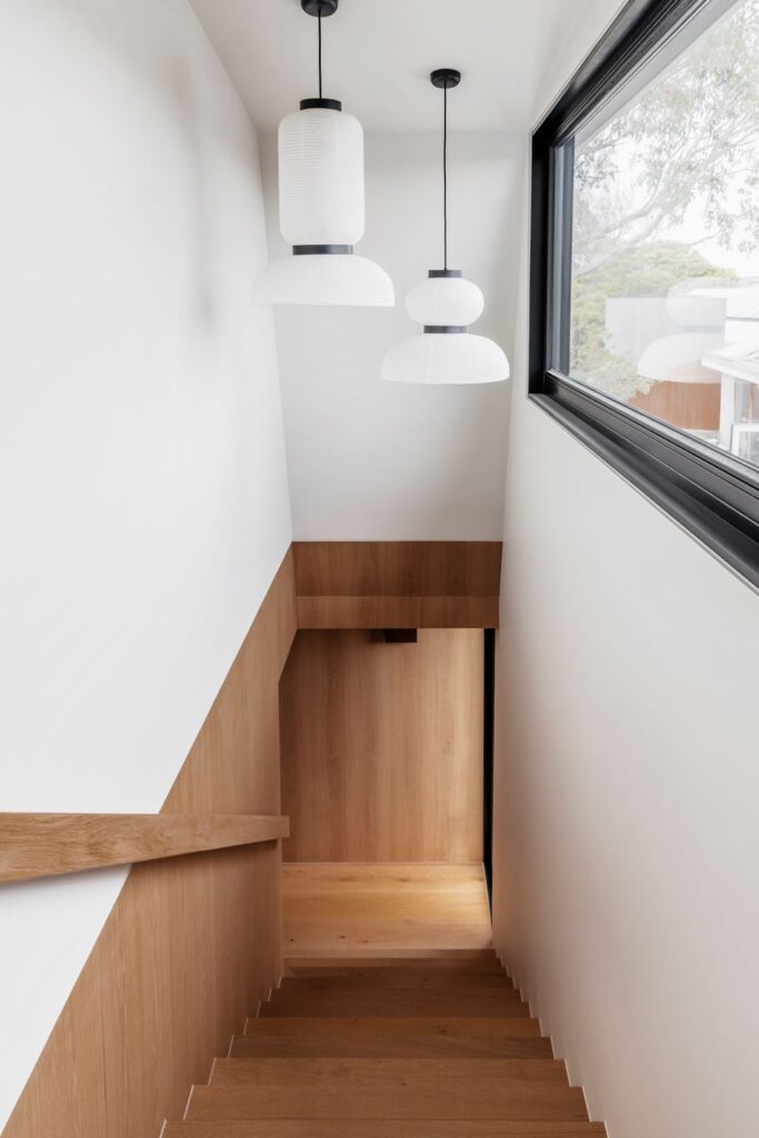 Minimalist wooden staircase and white pendant lights