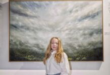 Light and memory: The atmospheric landscapes of Kelly Kondis Artist Kelly Kondis standing in front of large oil landscape