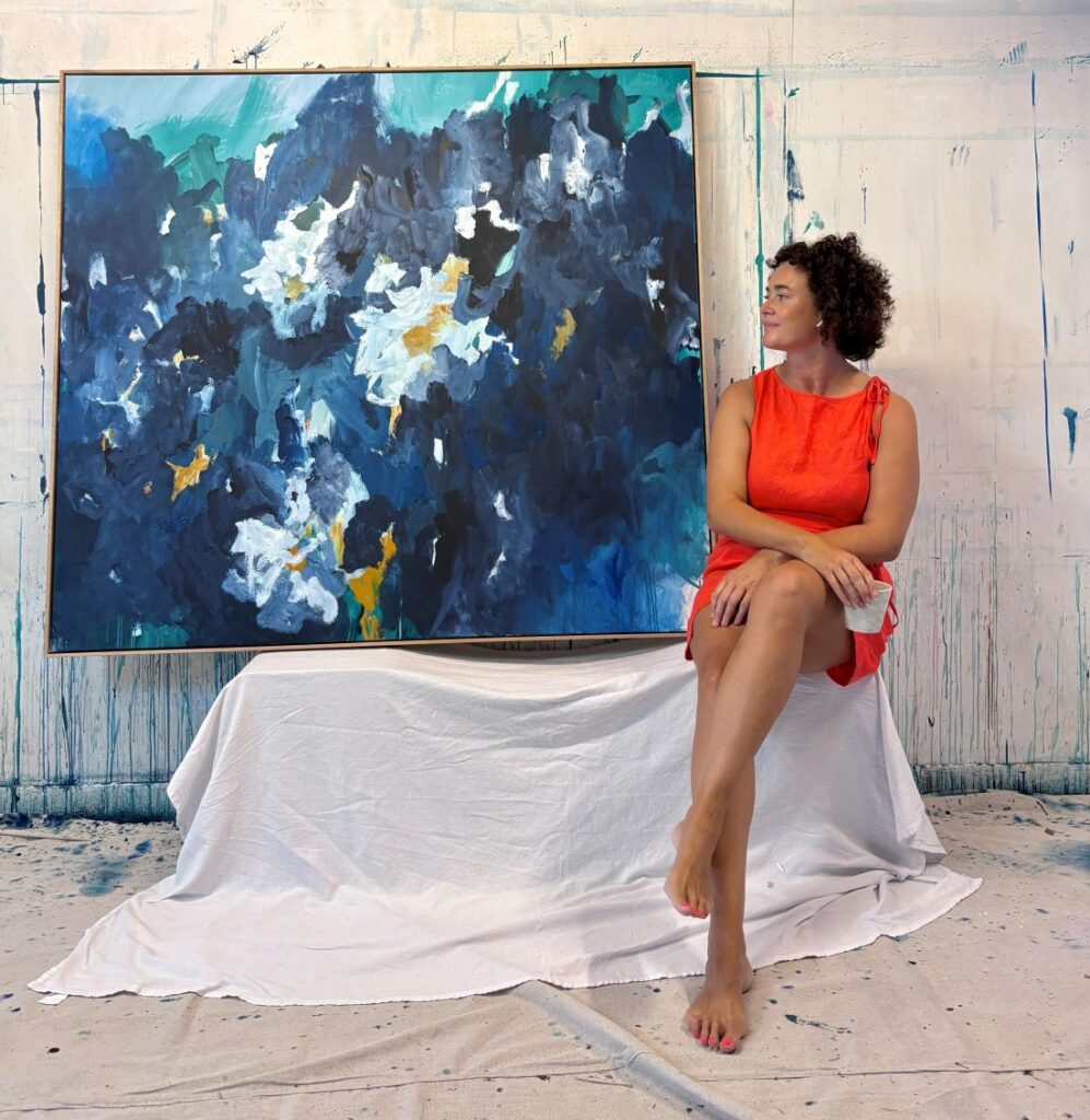 Artist portrait with large blue abstract floral painting