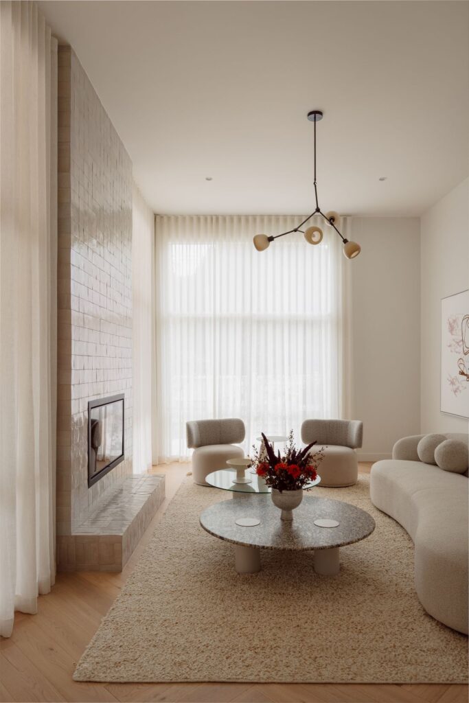 Hampton formal living room with a Moroccan Zellige tiled fireplace, curved cream seating, round coffee tables and soft sheer curtains