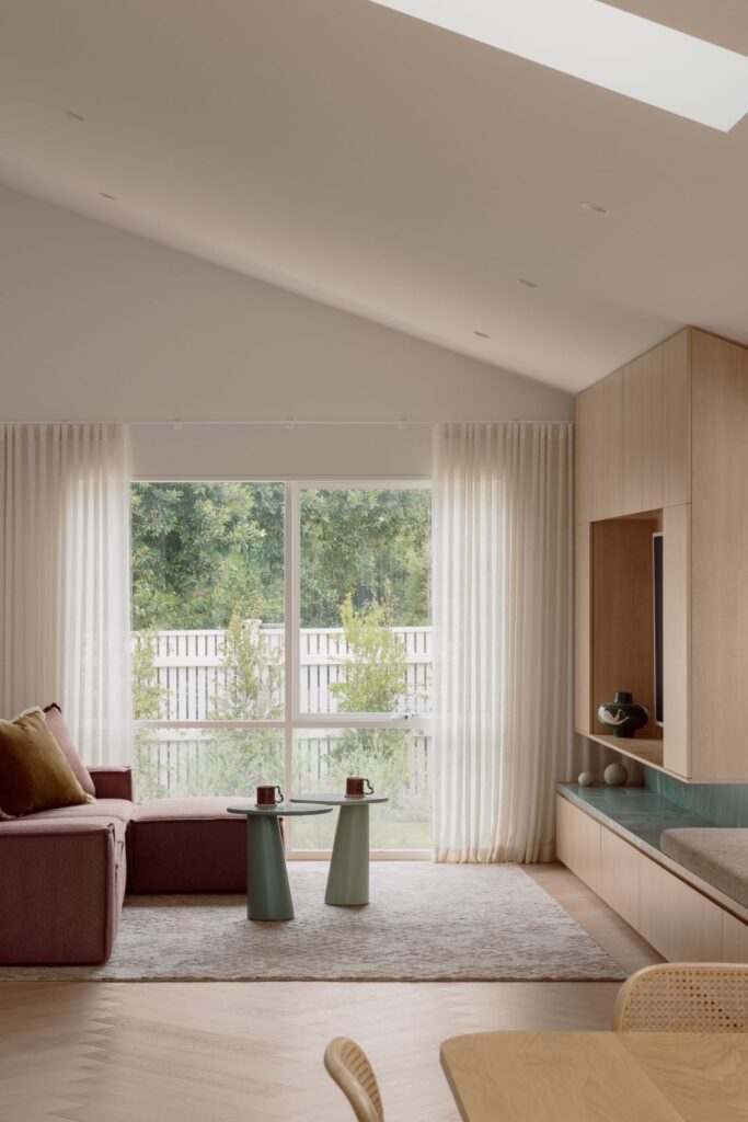 Hampton family living room with pale timber joinery, green quartzite bench, blush sofa, sheer curtains and herringbone timber flooring.