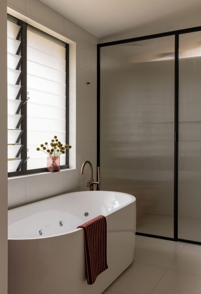 Soaking tub with reeded glass partition in ensuite