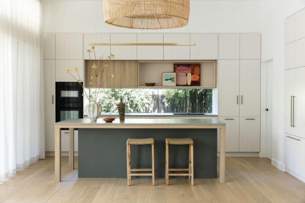 Waterhousia kitchen featuring white cabinetry, timber joinery, green island bench, woven pendant light, open shelving and natural styling details.