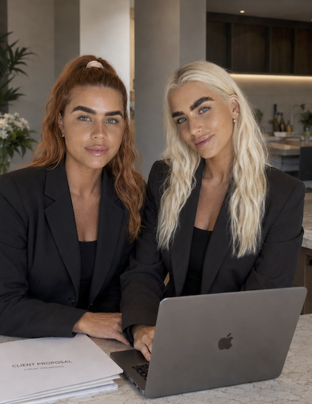 Natalie and Lilly from That Organised Life sitting together with a laptop and client documents in a modern home interior.