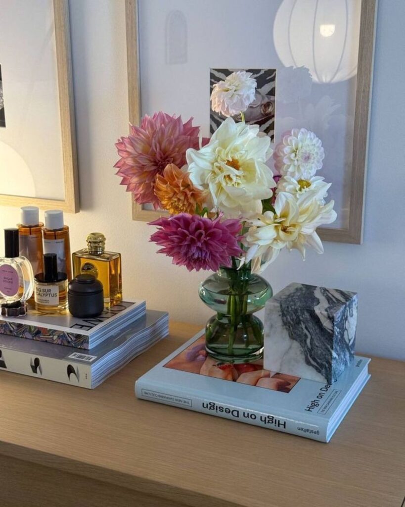 Colorful dahlia bouquet in green glass vase on dresser