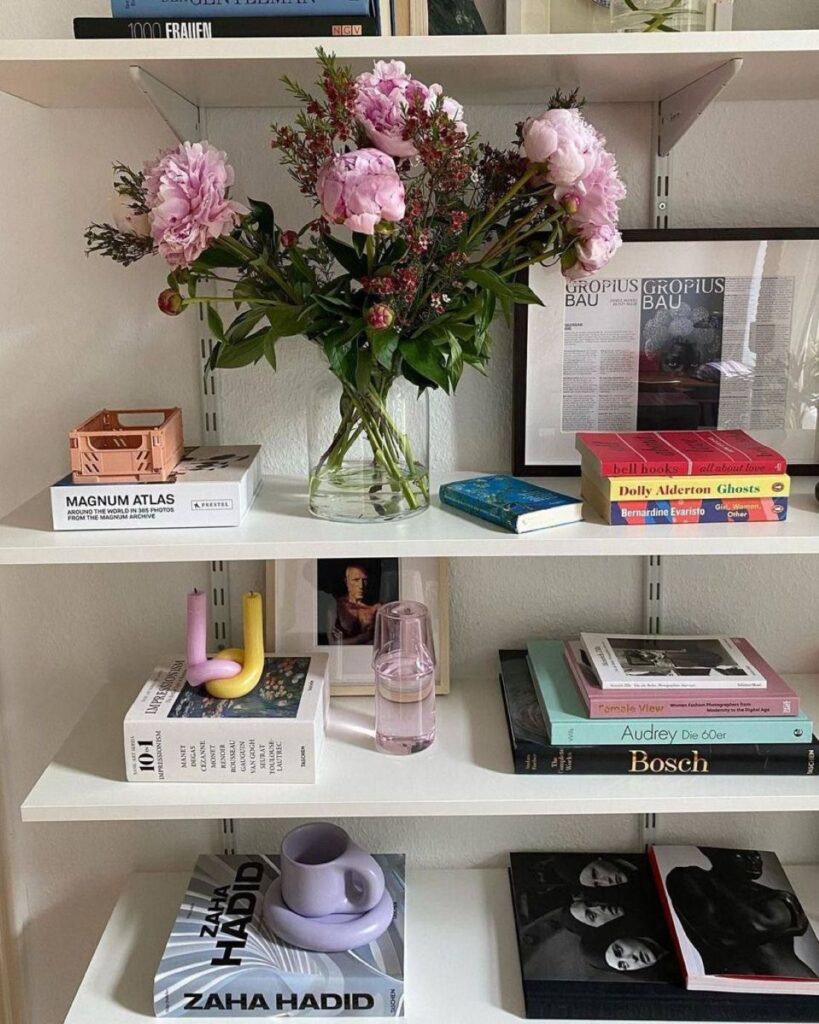 Lush pink peonies in clear vase on white open shelves
