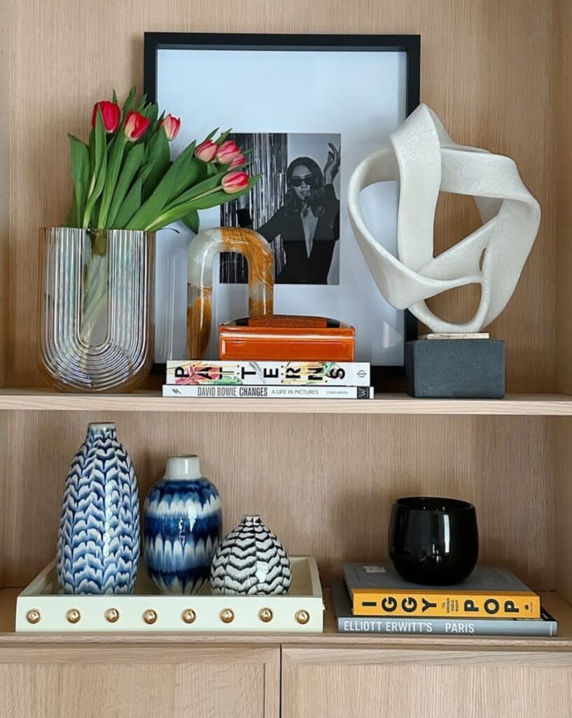 Red tulips in ribbed glass vase on wooden bookshelf