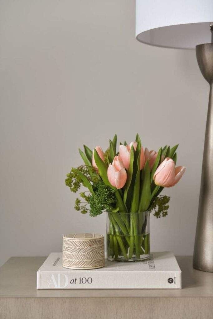 Soft pink tulips on bedside book stack